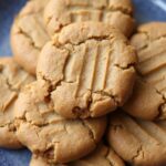 Stack of freshly baked vegan peanut butter cookies on a white plate